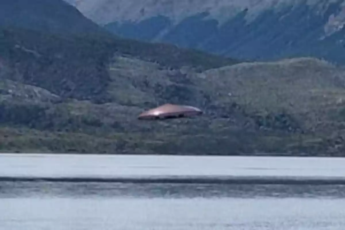 An unidentified flying object over a mountainous landscape and a lake.