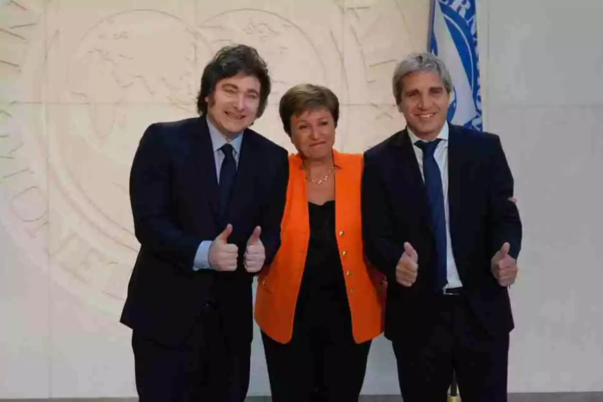 Tres personas posan juntas sonriendo y levantando los pulgares en un entorno formal.