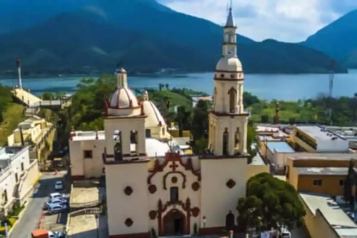 Aerial view of a colonial church with mountains and a lake in the background.