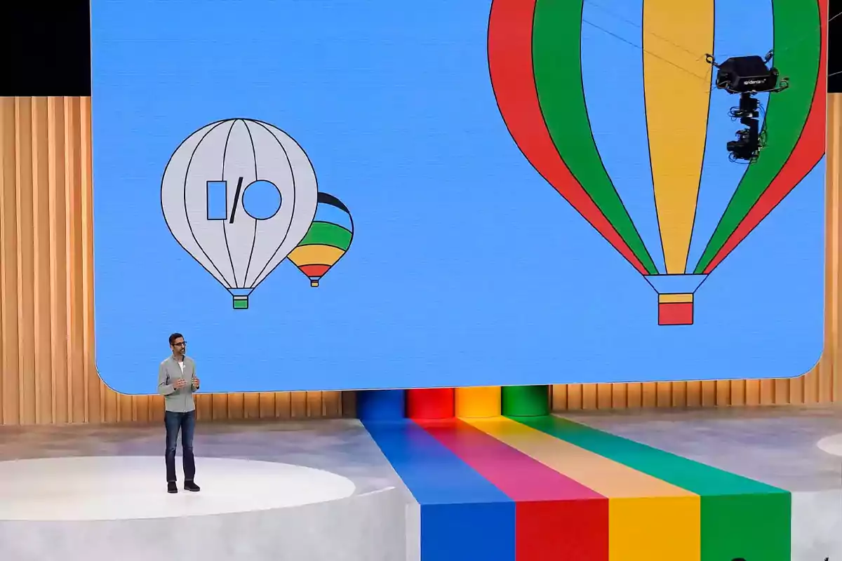 A presenter on a stage in front of a large screen displaying illustrations of hot air balloons. A presenter on a stage in front of a large screen displaying illustrations of hot air balloons.