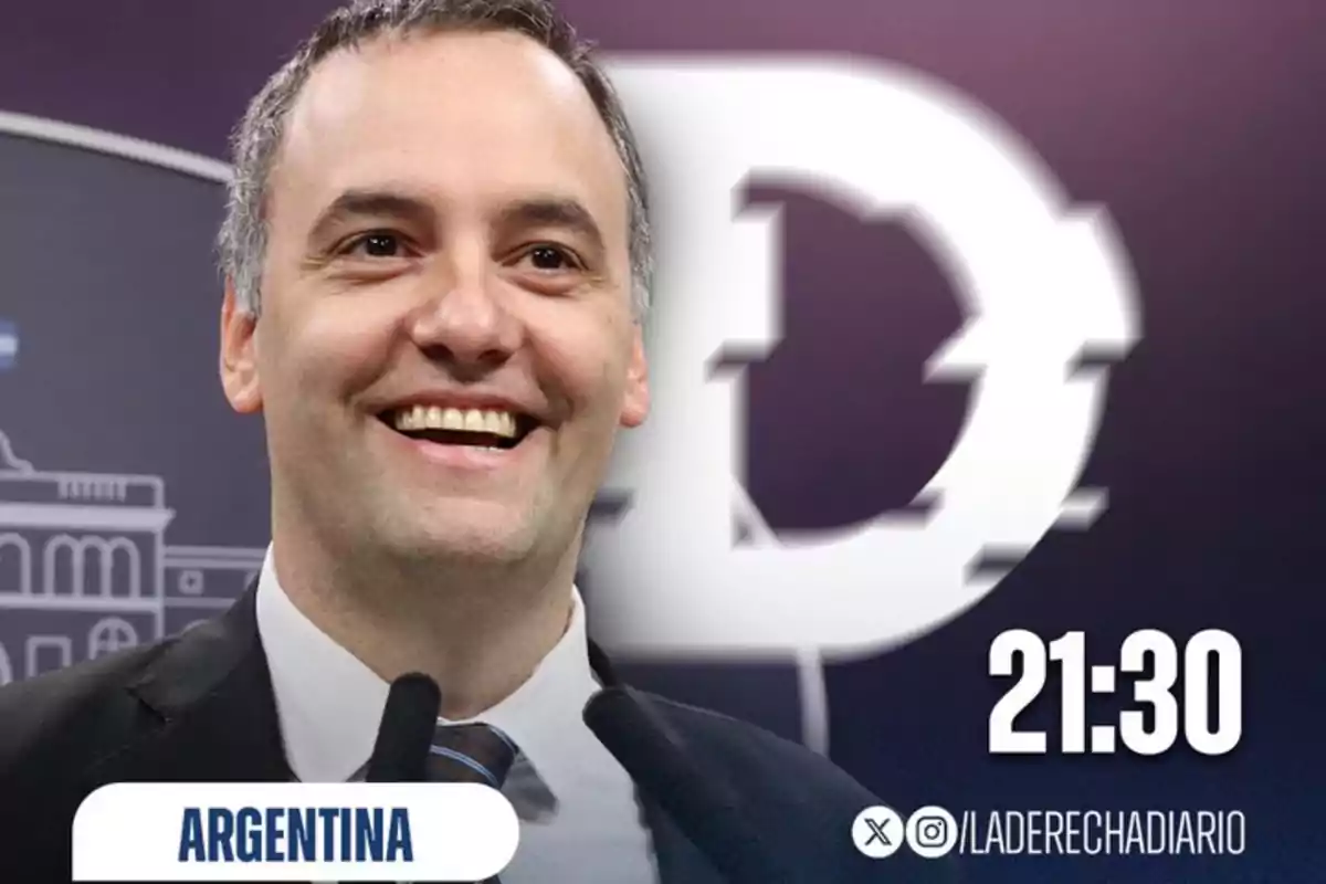 Hombre sonriendo con fondo morado y un logotipo blanco detrás, texto que indica Hombre sonriendo con fondo morado y un logotipo blanco detrás, texto que indica