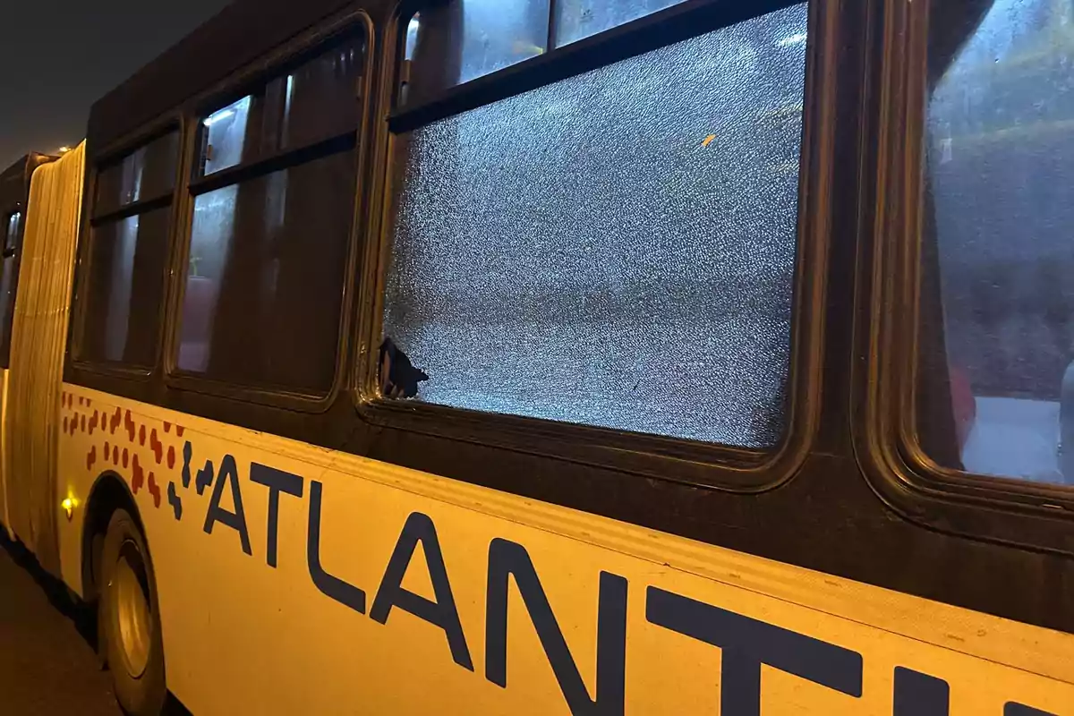 Un autobús con una ventana rota y el logo parcialmente visible. Un autobús con una ventana rota y el logo parcialmente visible.
