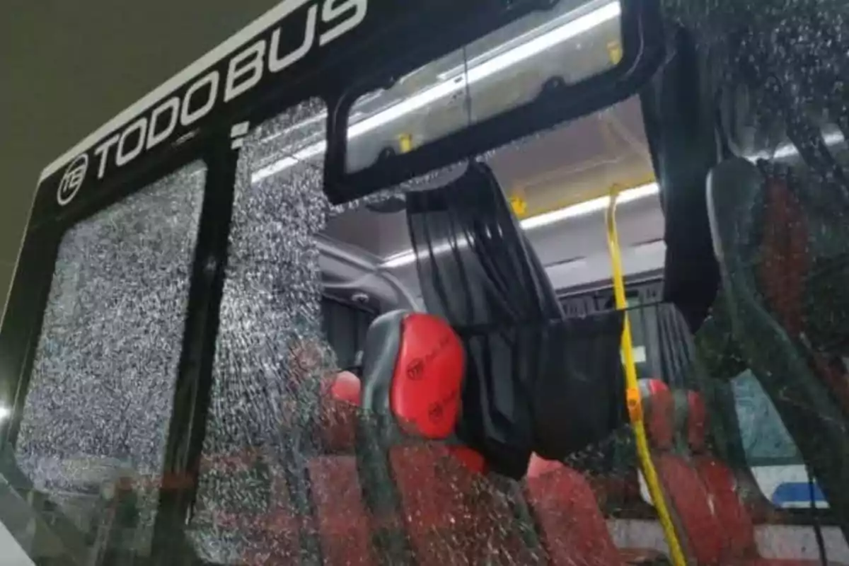 Un autobús con una ventana rota y asientos rojos en su interior.