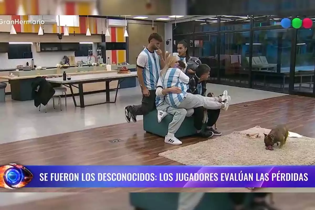 A group of people wearing Argentina jerseys gathers in a modern room while a dog plays on a rug, and at the bottom of the image there is a banner with a message about players assessing losses. A group of people wearing Argentina jerseys gathers in a modern room while a dog plays on a rug, and at the bottom of the image there is a banner with a message about players assessing losses.