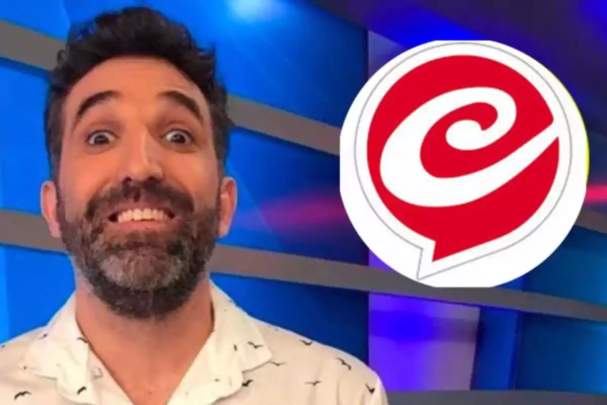 Un hombre sonriente con barba y cabello oscuro está frente a un fondo azul con un logotipo rojo y blanco a su lado.