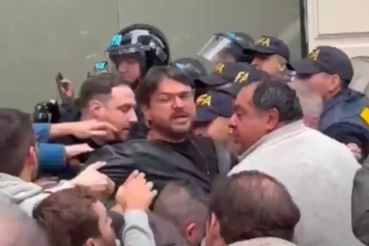 Un grupo de personas forcejea con la policía en una situación de tensión y empujones
