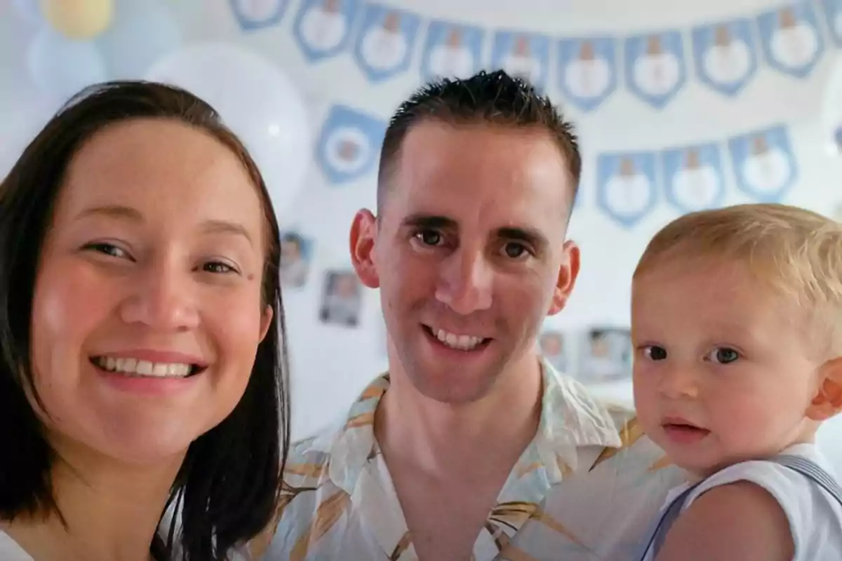 Una familia sonriente posa para una foto en una fiesta con decoración azul y blanca al fondo