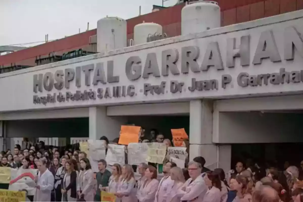Facade of the Garrahan Hospital with a group of people and healthcare professionals gathered holding protest signs