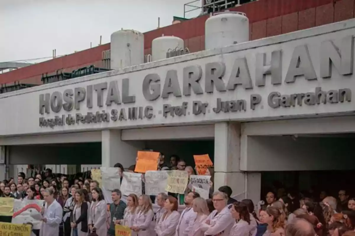 Facade of the Garrahan Hospital with a group of people gathered holding signs in front of the main entrance