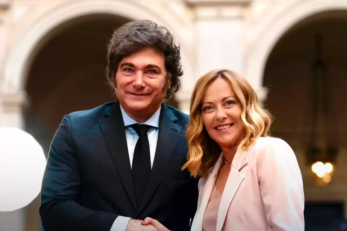 Dos personas sonríen y se dan la mano en un entorno formal con un fondo arquitectónico elegante