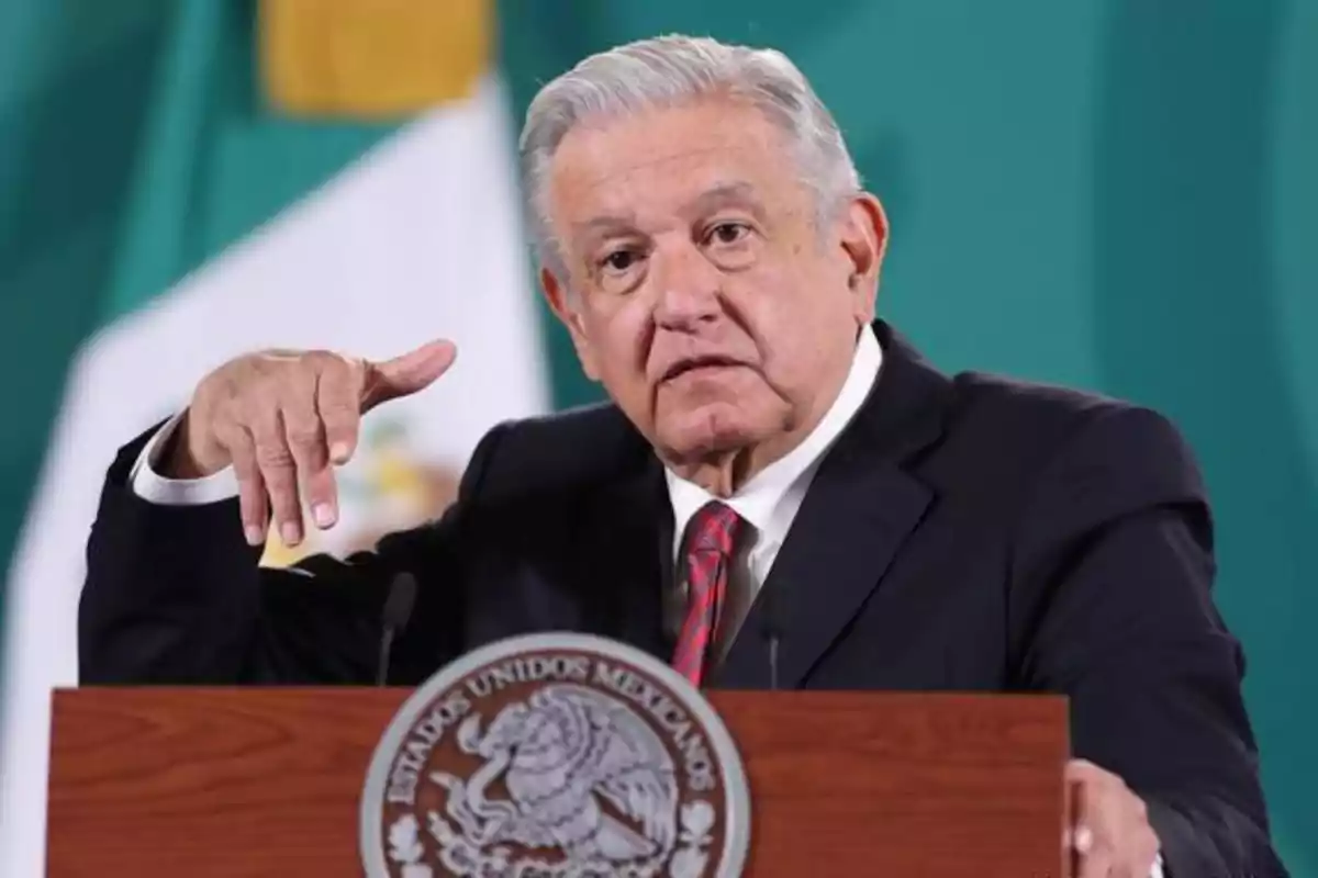 Un hombre de cabello canoso y traje oscuro gesticula mientras habla detrás de un podio con el escudo nacional de México. Un hombre de cabello canoso y traje oscuro gesticula mientras habla detrás de un podio con el escudo nacional de México.