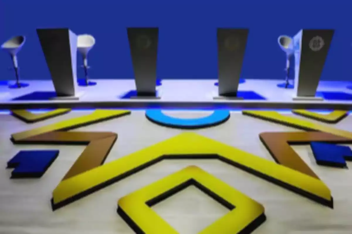 A stage with podiums and modern chairs on a floor with geometric patterns in blue, yellow, and brown colors.