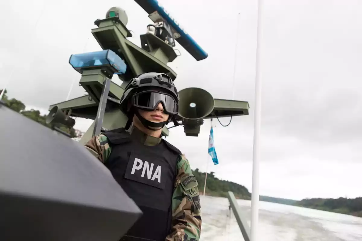 Un miembro de la Prefectura Naval Argentina con uniforme y equipo de protección en una embarcación patrullera.