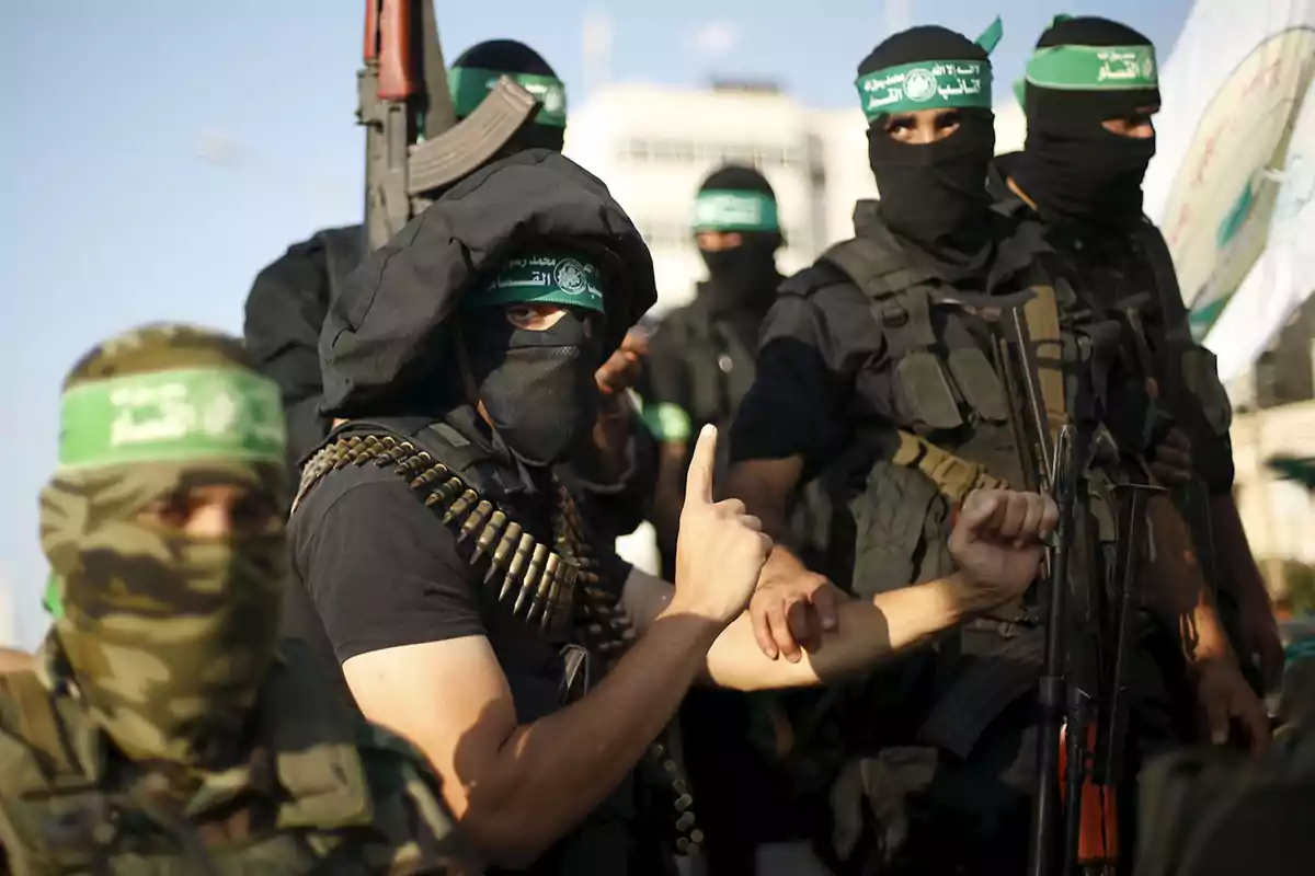 Un grupo de personas enmascaradas vestidas de negro con armas y municiones.