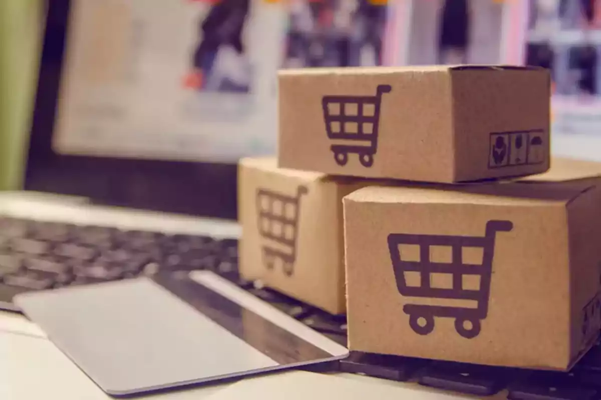 Cardboard boxes with a shopping cart icon on a computer keyboard next to a credit card. Cardboard boxes with a shopping cart icon on a computer keyboard next to a credit card.