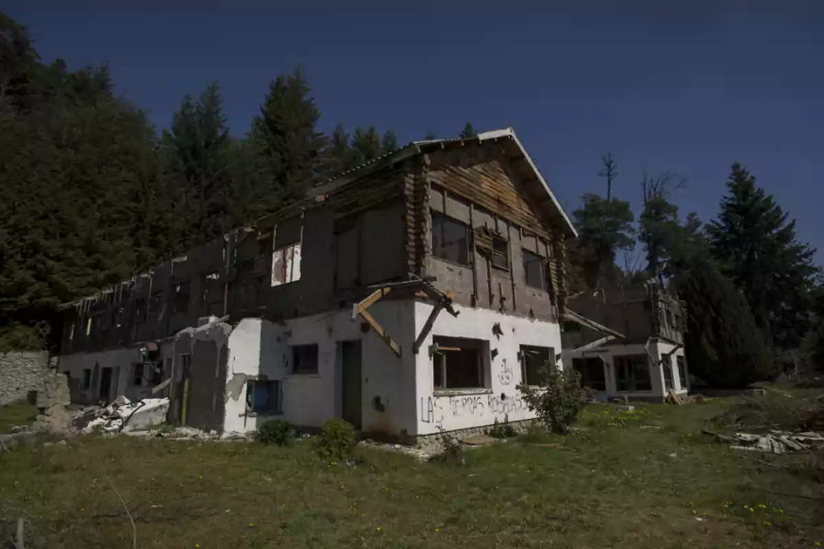 Abandoned and deteriorated building surrounded by trees and vegetation on a sunny day Abandoned and deteriorated building surrounded by trees and vegetation on a sunny day