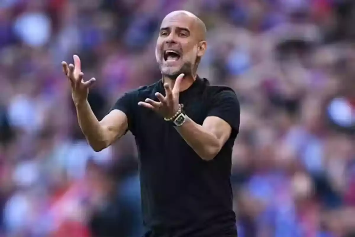 A bald man with a beard and a black t-jersey gestures in a stadium. A bald man with a beard and a black t-jersey gestures in a stadium.