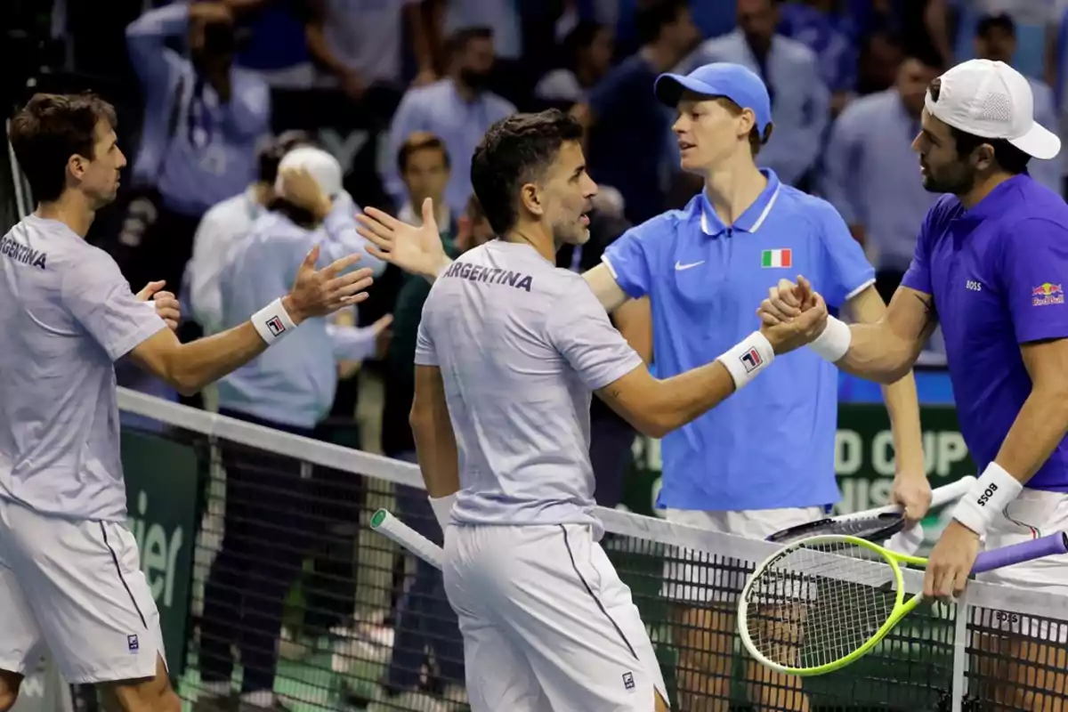 Jugadores de tenis de Argentina e Italia se saludan en la red después de un partido.