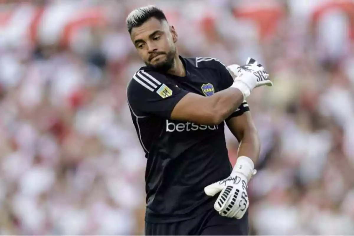 Un jugador de fútbol con uniforme negro y guantes blancos en el campo. Un jugador de fútbol con uniforme negro y guantes blancos en el campo.