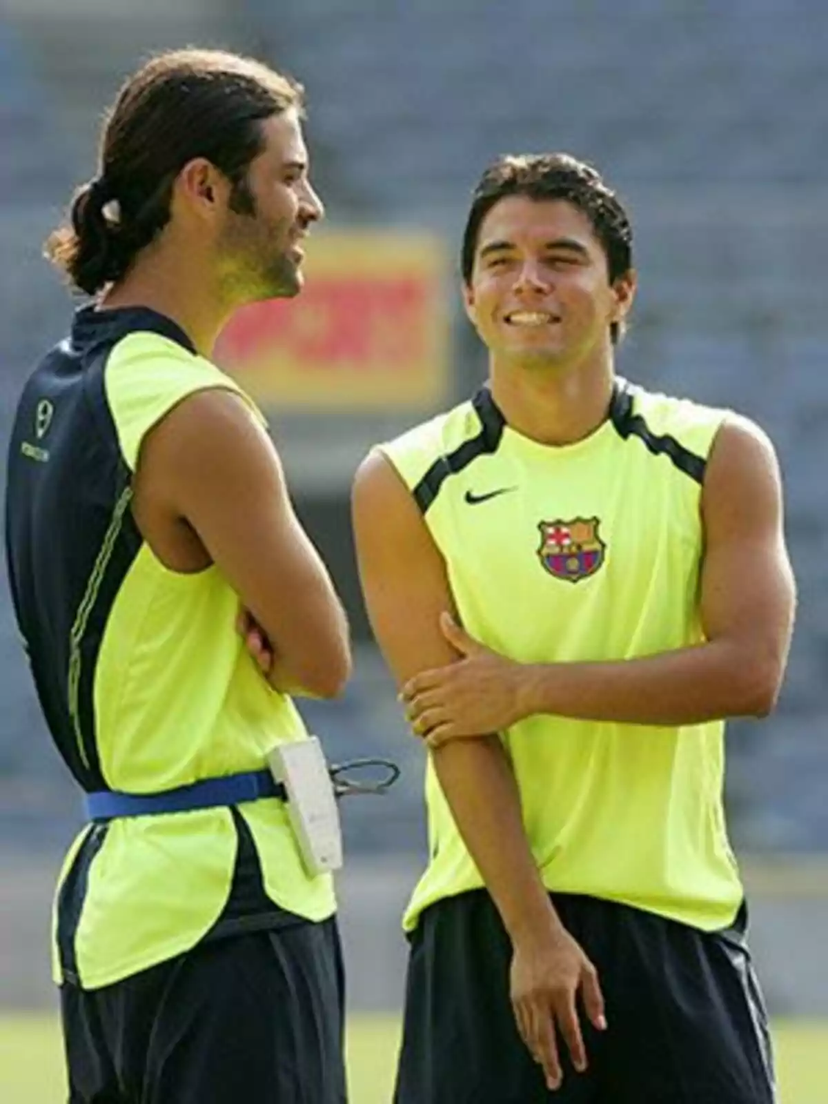 Dos futbolistas con uniforme de entrenamiento del Barcelona conversan y sonríen en una cancha Dos futbolistas con uniforme de entrenamiento del Barcelona conversan y sonríen en una cancha