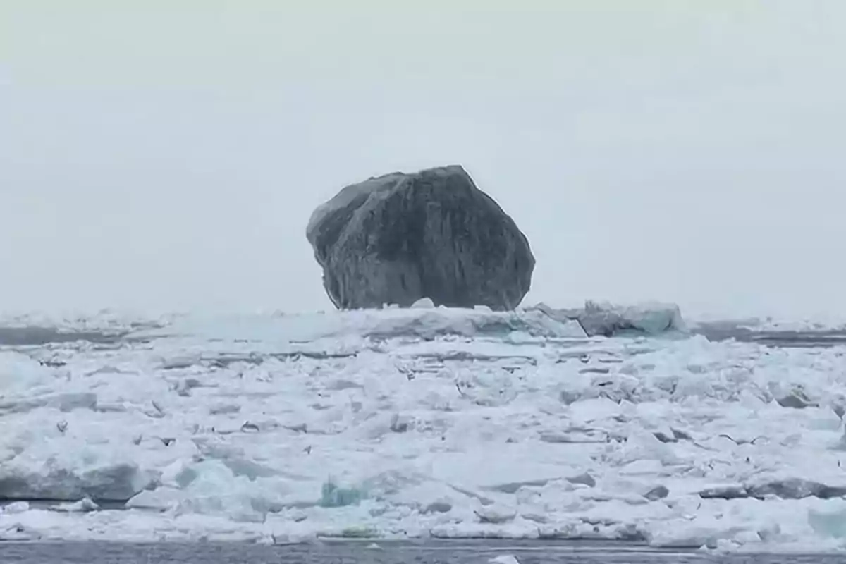 Large dark rock over a landscape covered with ice and snow in a cold and cloudy environment Large dark rock over a landscape covered with ice and snow in a cold and cloudy environment