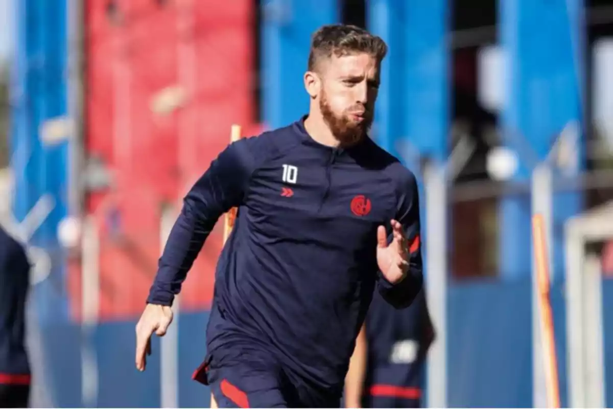 Un jugador de fútbol entrenando en un campo con uniforme azul oscuro. Un jugador de fútbol entrenando en un campo con uniforme azul oscuro.