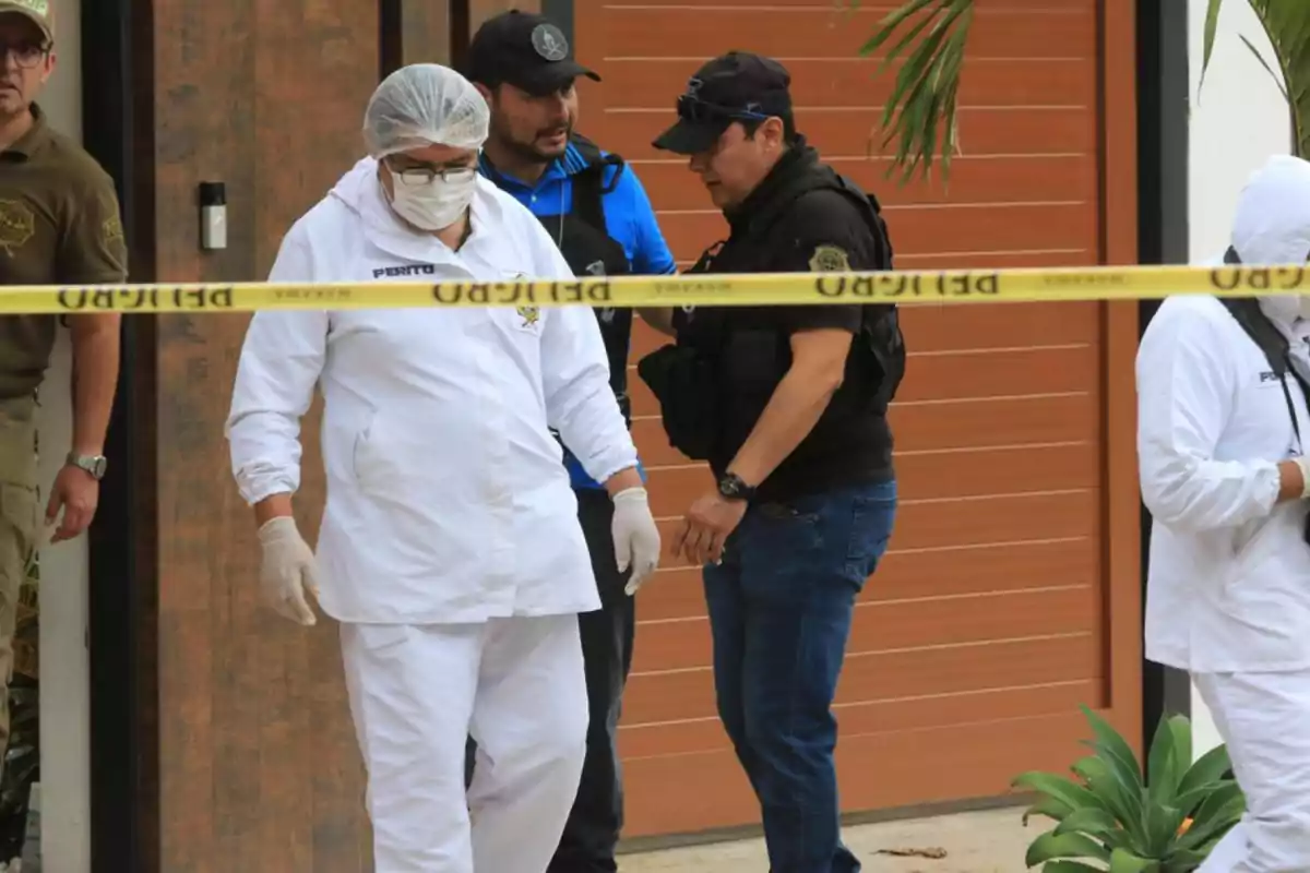 Personas con equipo forense y policial trabajando en una escena delimitada por cinta amarilla.