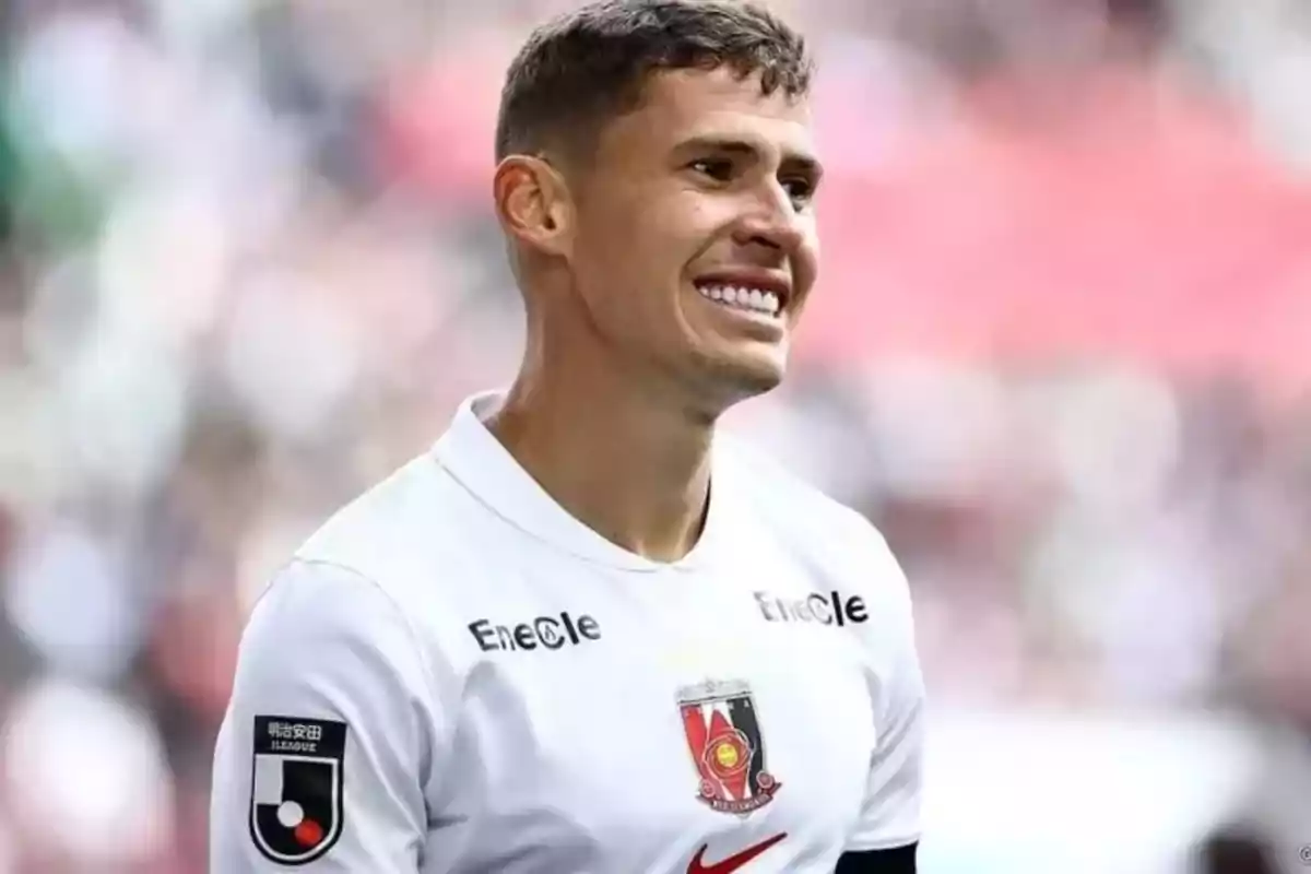 Soccer player in a white uniform smiles in a stadium during a match Soccer player in a white uniform smiles in a stadium during a match