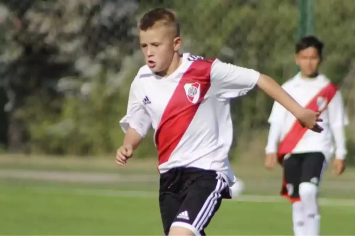 Un joven futbolista corriendo en el campo con el uniforme de River Plate. Un joven futbolista corriendo en el campo con el uniforme de River Plate.