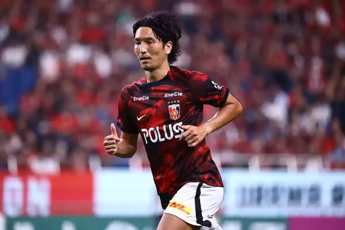 Soccer player wearing a red and black jersey running in a stadium during a match Soccer player wearing a red and black jersey running in a stadium during a match