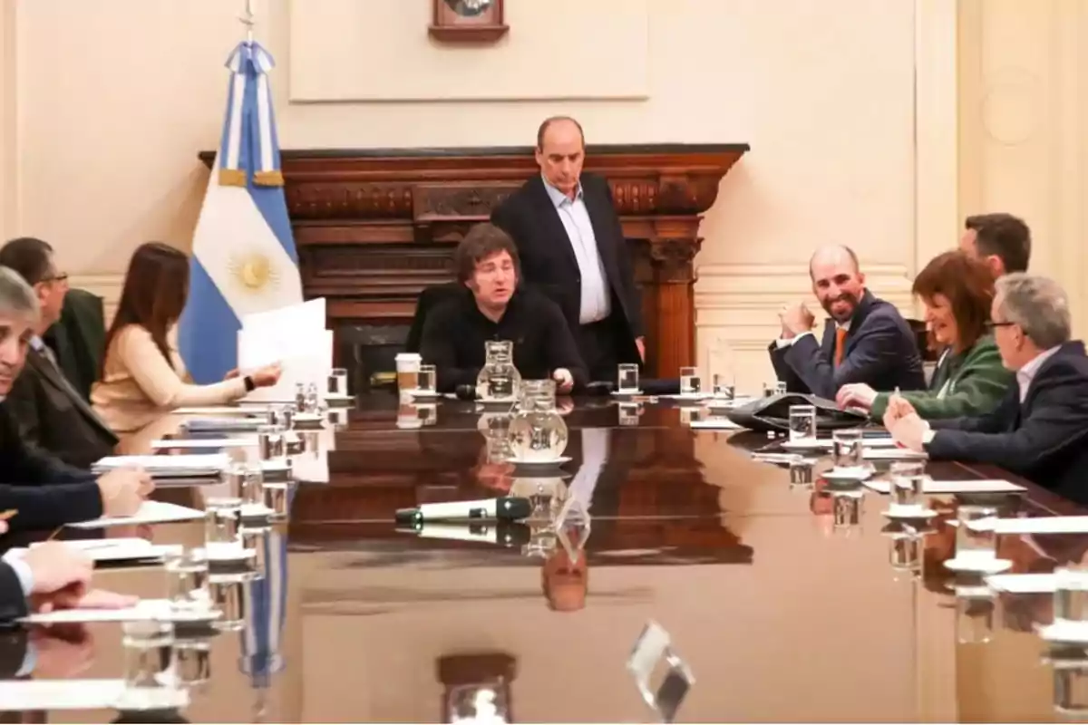 Personas sentadas alrededor de una mesa de reuniones en una sala con una bandera de Argentina en el fondo.