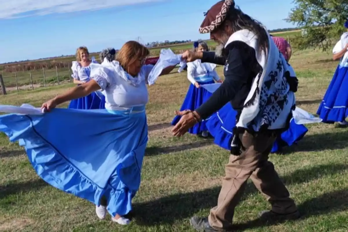 Personas bailando en un campo, vestidas con trajes tradicionales azules y blancos. Personas bailando en un campo, vestidas con trajes tradicionales azules y blancos.