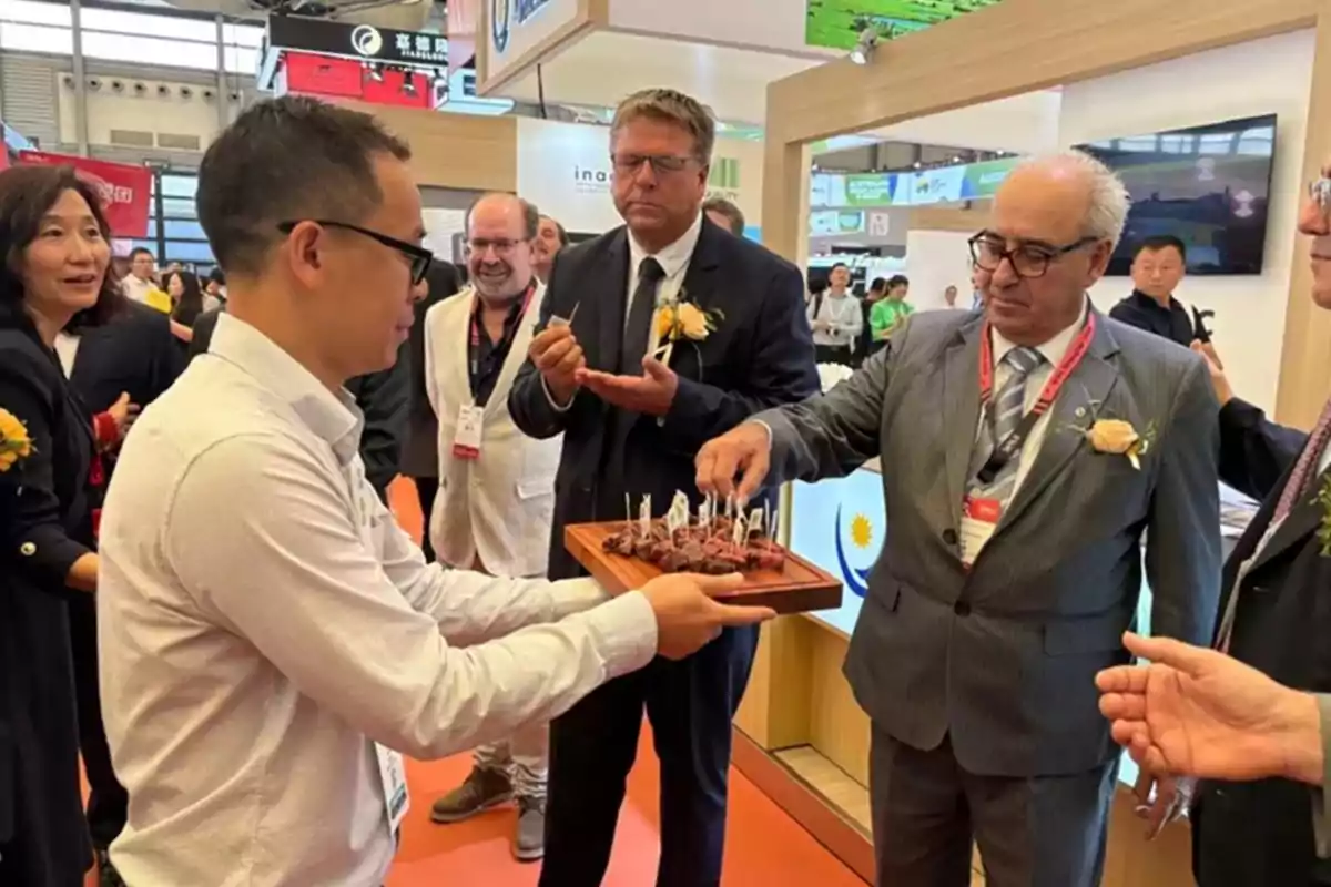 Un grupo de personas en un evento formal degustan aperitivos servidos en una bandeja. Un grupo de personas en un evento formal degustan aperitivos servidos en una bandeja.