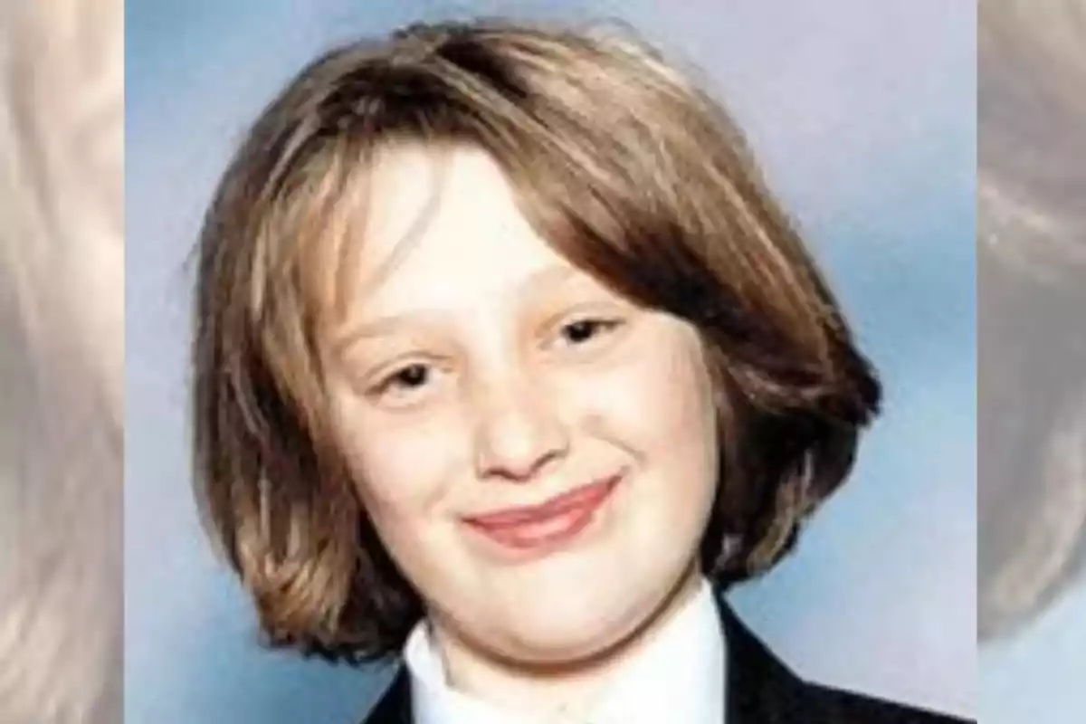 Una persona joven con cabello castaño claro y una expresión sonriente, vestida con una camisa blanca y chaqueta oscura, sobre un fondo azul.