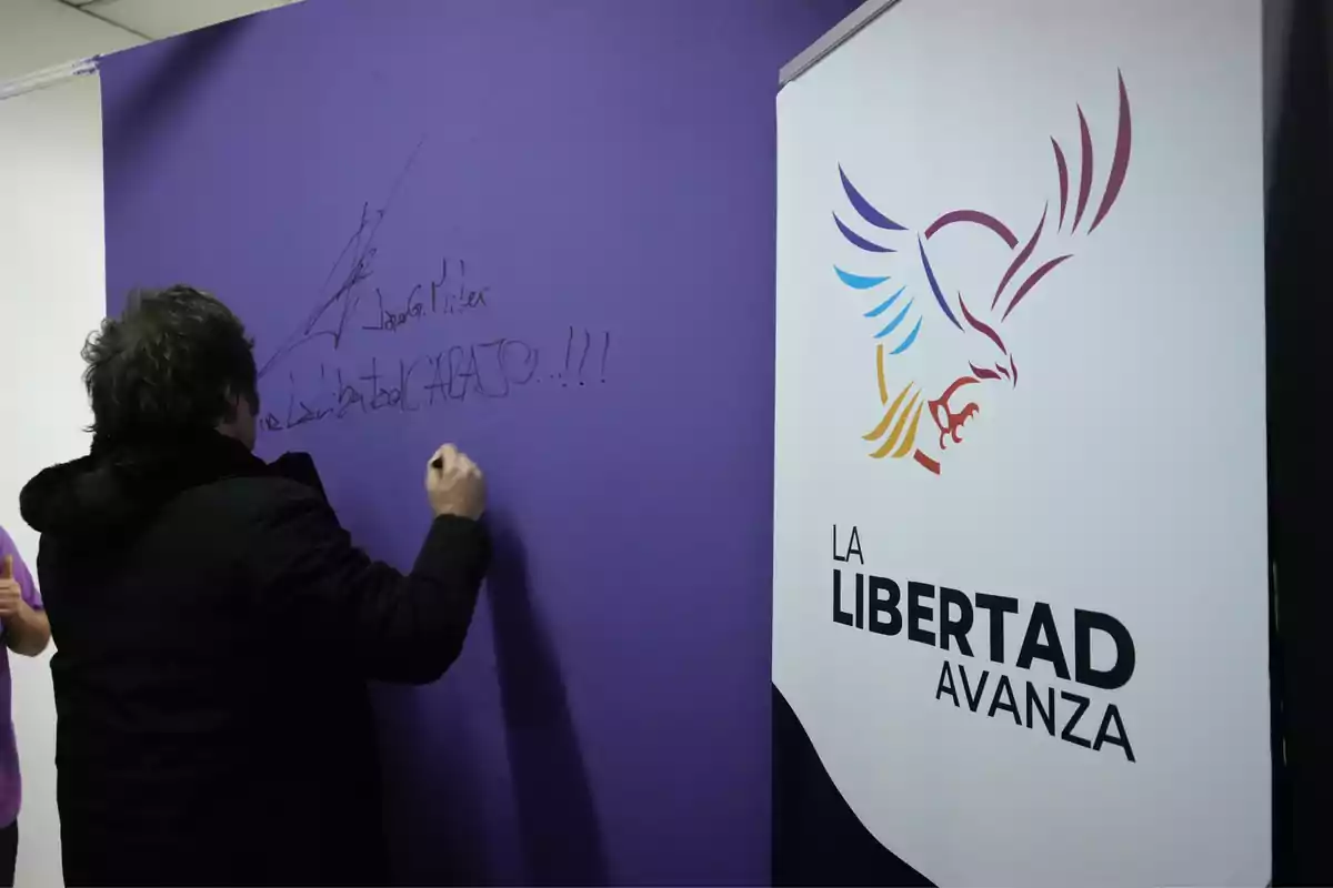 A person with their back turned signs a purple wall next to a sign that says A person with their back turned signs a purple wall next to a sign that says
