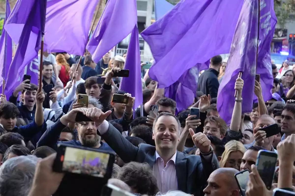 Un grupo de personas en una manifestación con banderas moradas y teléfonos móviles. Un grupo de personas en una manifestación con banderas moradas y teléfonos móviles.