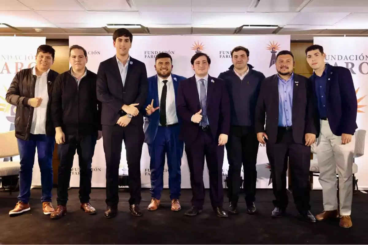 Un grupo de ocho hombres posando juntos en un evento de la Fundación Faro, todos vestidos de manera formal y sonriendo frente a un fondo con el logotipo de la organización.