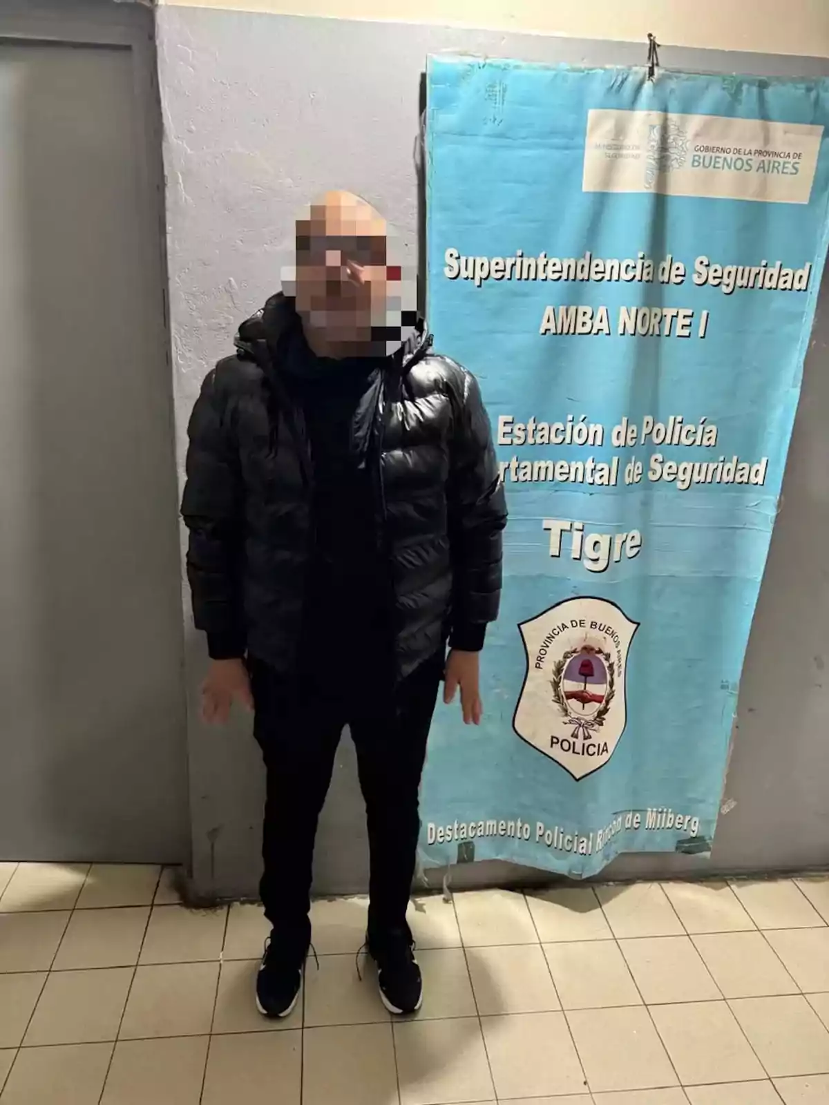 Person standing with a pixelated face in front of a Buenos Aires police sign at a police station Person standing with a pixelated face in front of a Buenos Aires police sign at a police station