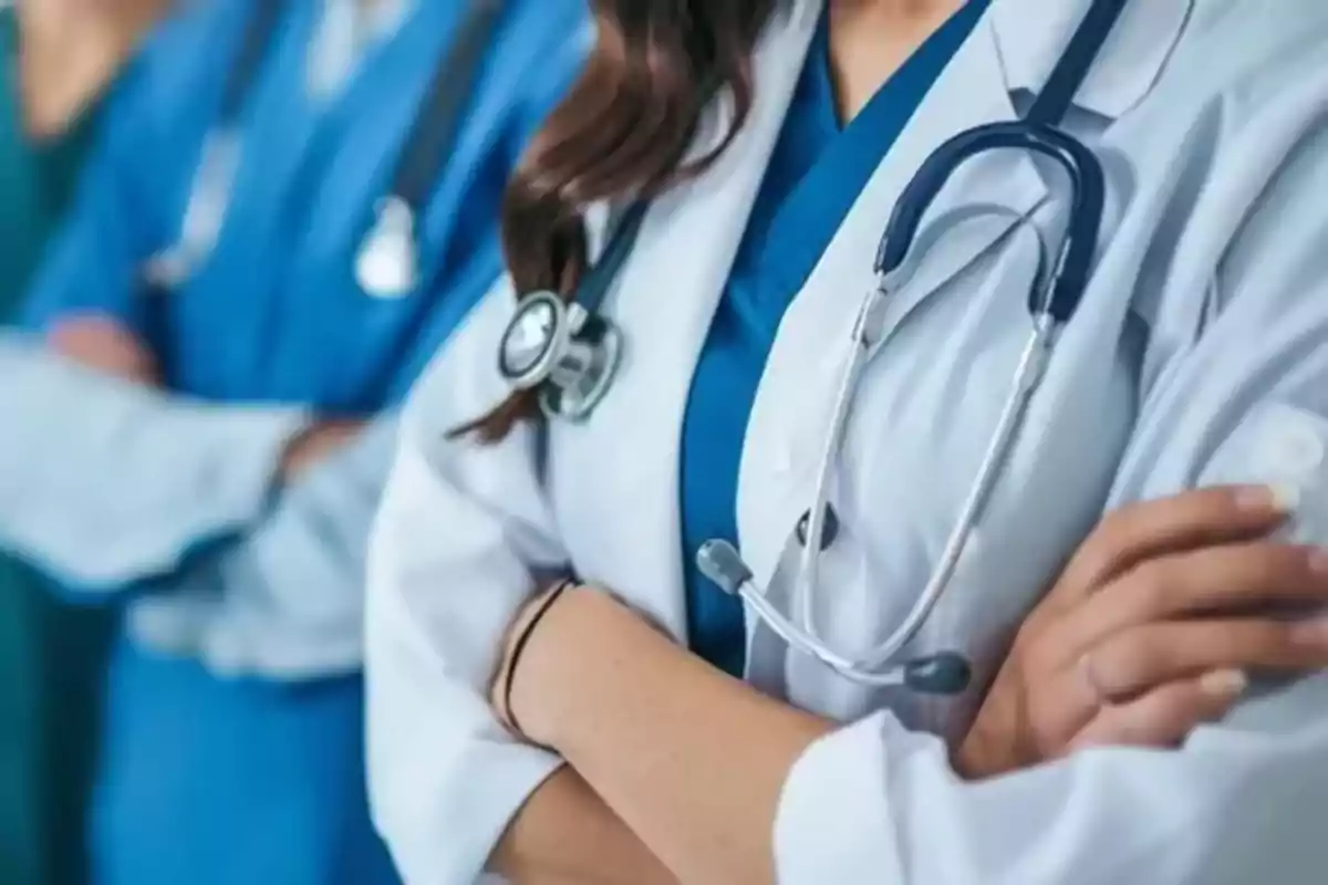 Grupo de profesionales de la salud con batas y estetoscopios cruzando los brazos Grupo de profesionales de la salud con batas y estetoscopios cruzando los brazos