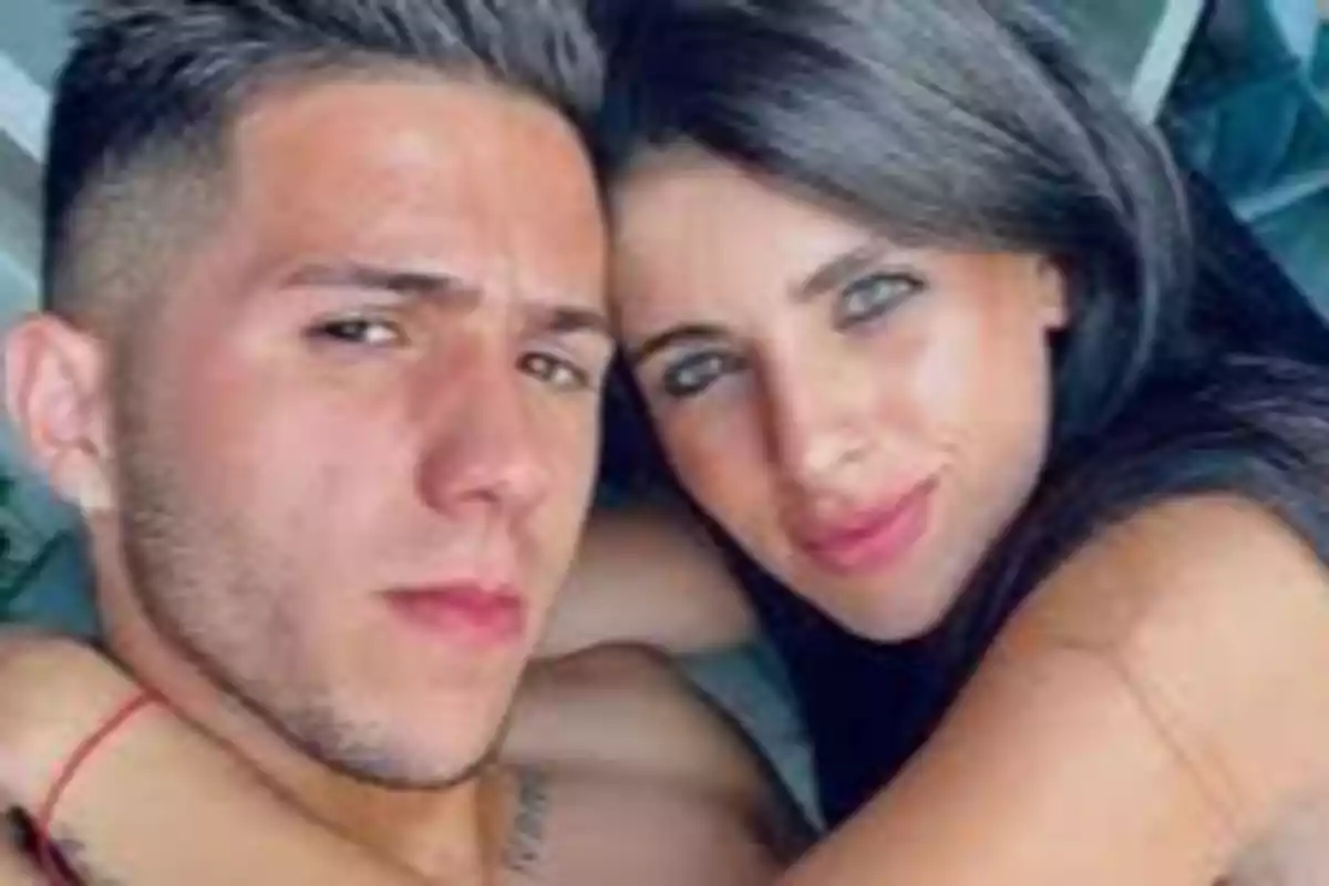 Una pareja joven abrazándose y sonriendo a la cámara.