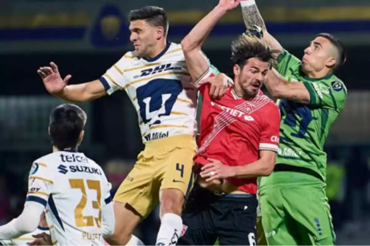 Jugadores de fútbol compiten por el balón en el aire durante un partido.