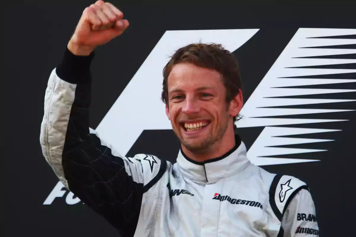 Piloto de carreras celebrando con el puño en alto y sonriendo en el podio.