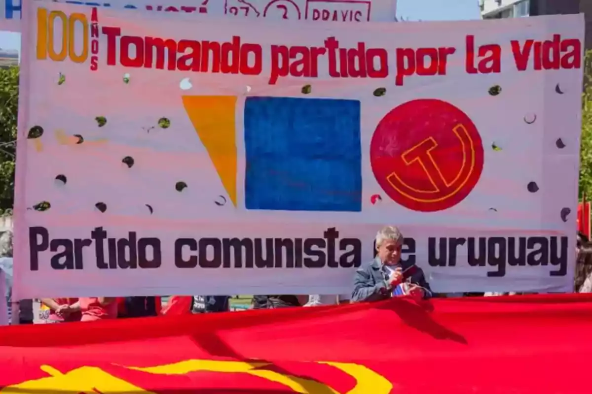 People hold a banner of the Communist Party of Uruguay at a demonstration, with the text People hold a banner of the Communist Party of Uruguay at a demonstration, with the text