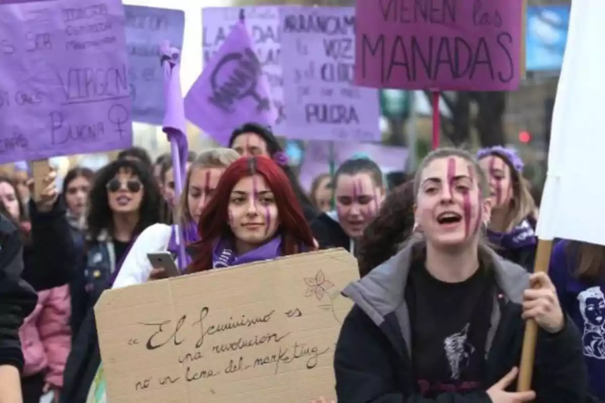 Un grupo de personas participa en una manifestación feminista, sosteniendo pancartas y carteles con mensajes de protesta.