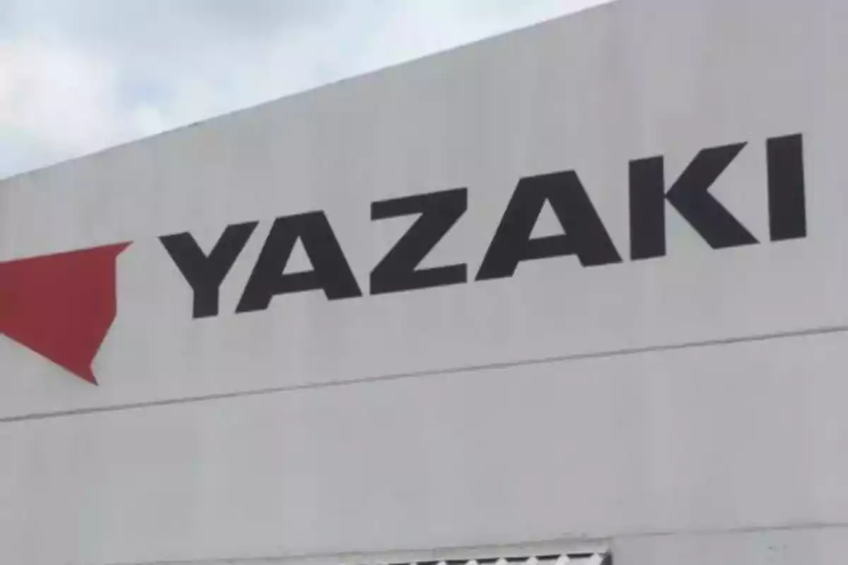 Edificio con el logotipo de Yazaki en letras negras sobre un fondo blanco.