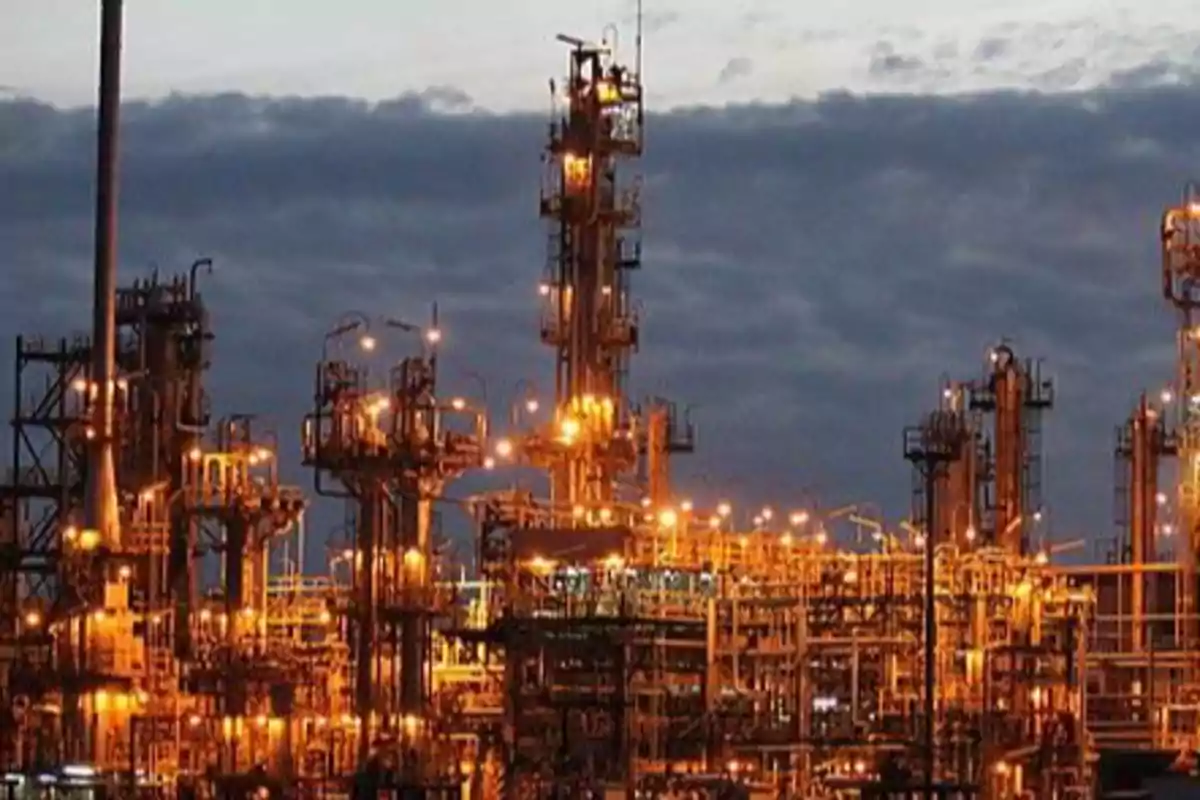 An industrial plant illuminated at dusk with metal structures and bright lights.