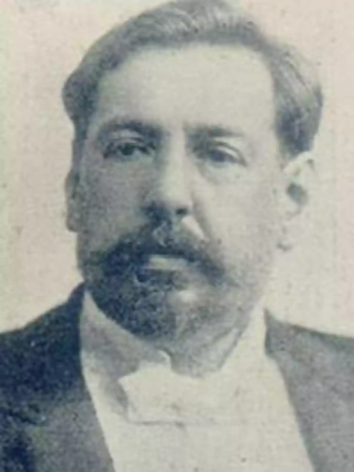 Un retrato en blanco y negro de un hombre con barba y bigote, vistiendo un traje formal.