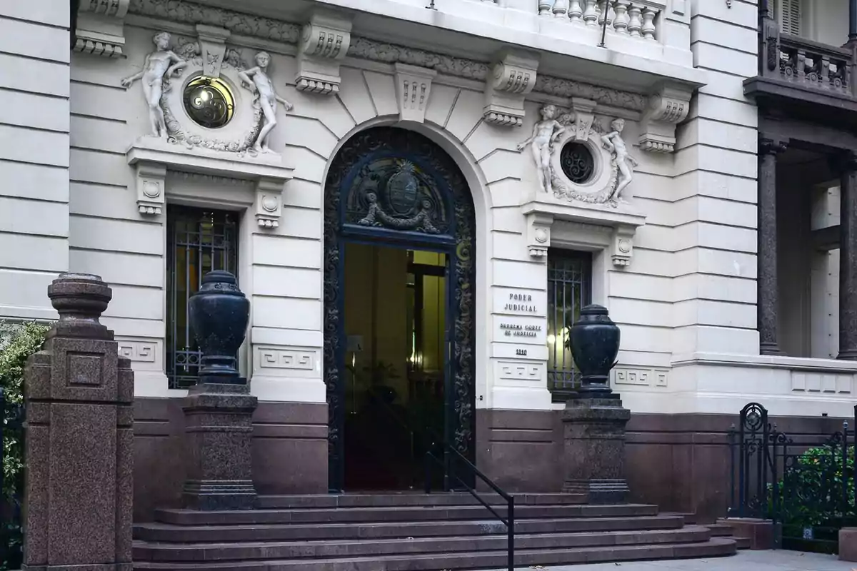 Entrada de un edificio histórico con detalles arquitectónicos ornamentados y una puerta de hierro forjado.