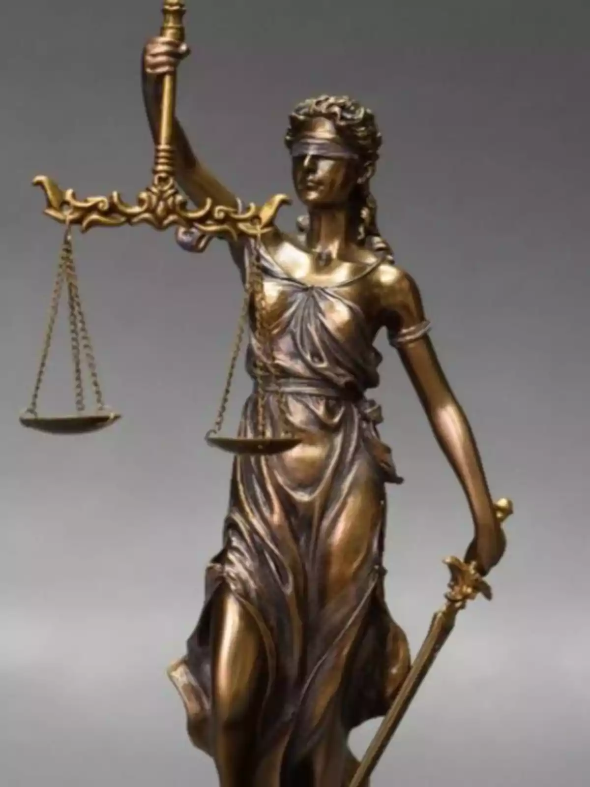 A bronze statue of the blindfolded goddess of justice, holding a scale in one hand and a sword in the other.