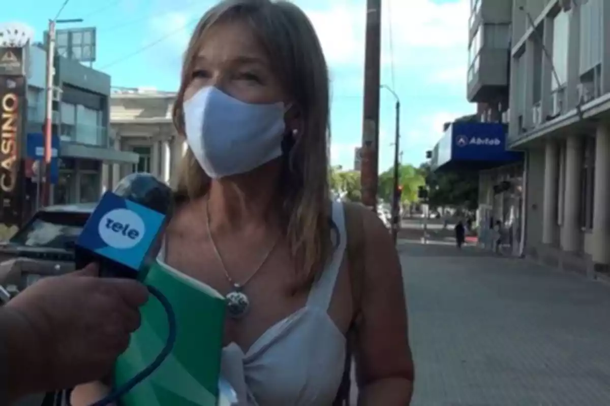 Woman with a mask being interviewed on the street by a television channel.